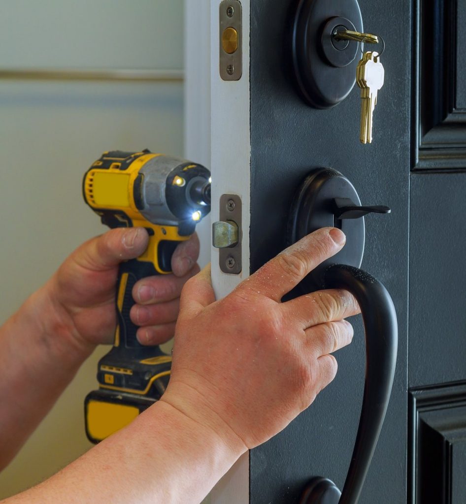 closeup of a professional locksmith installing a new lock on a house exterior door on the inside